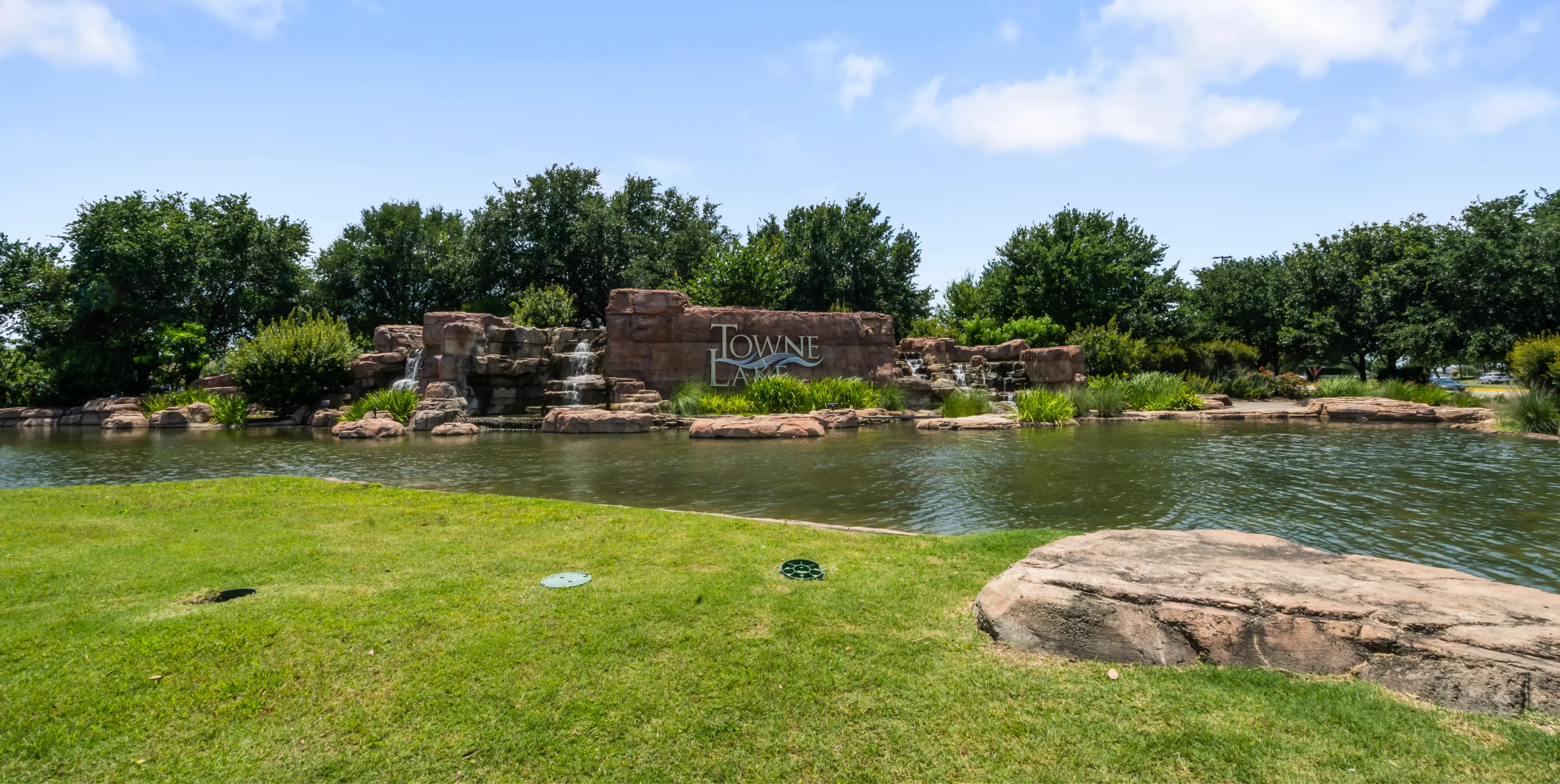 a pond in a park with rocks and trees